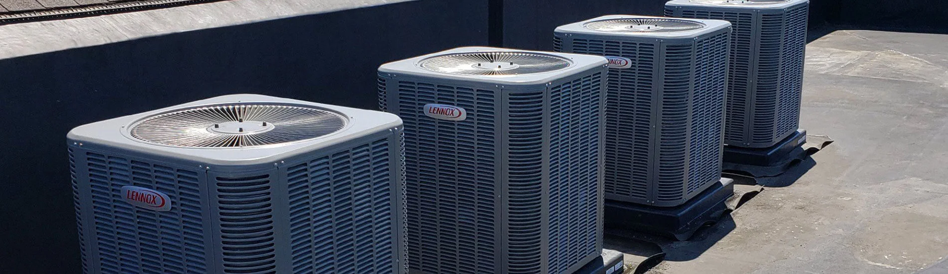 Rows of commercial rooftop HVAC units on a flat commercial building roof